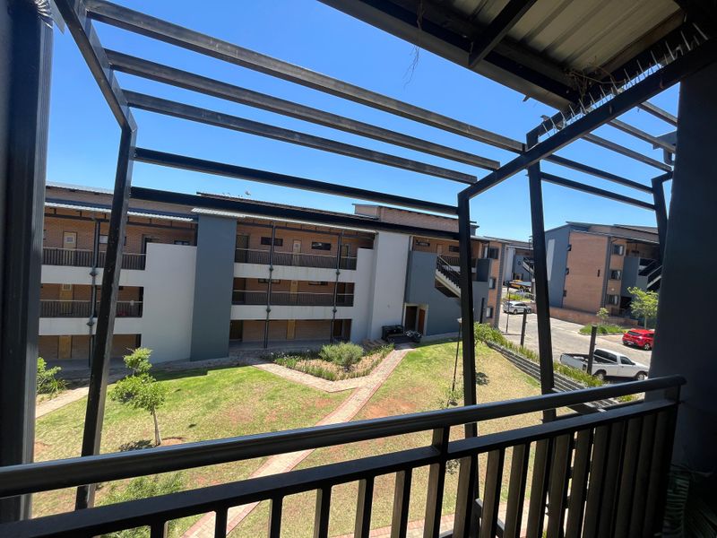 A view from a balcony overlooking a communal garden area and apartment complex buildings.
