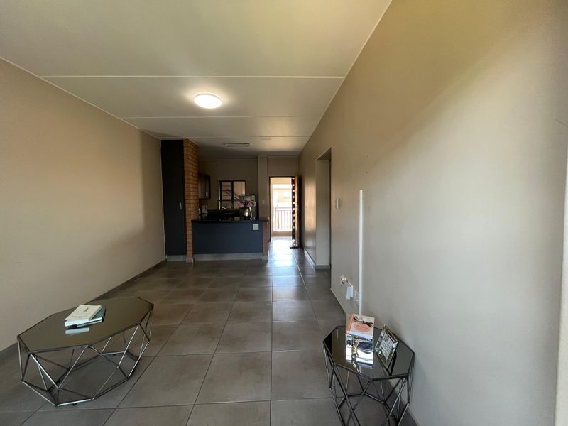 Open plan living area featuring tiled flooring, an exposed brick feature column, and a kitchen with a breakfast counter.