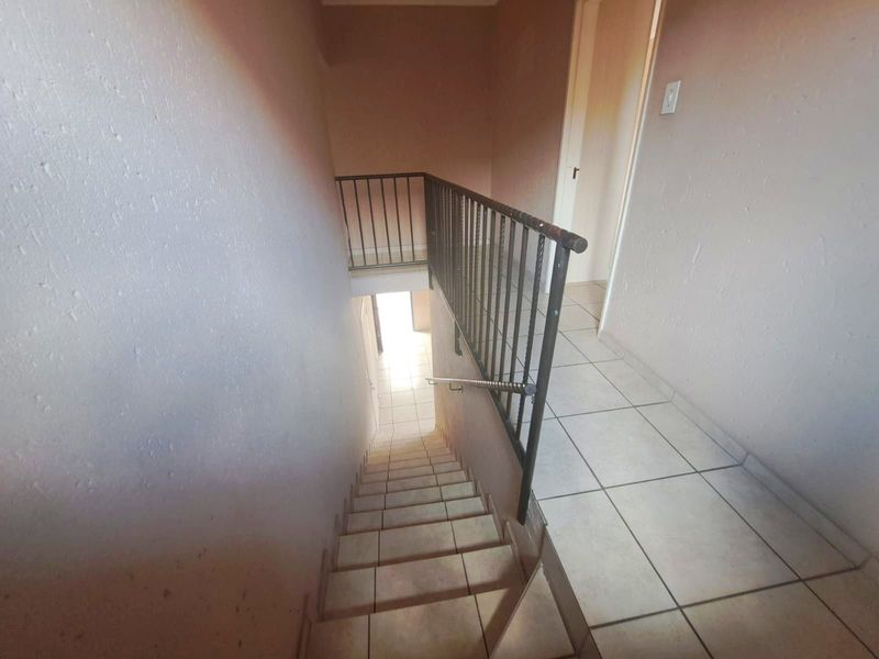 A functional staircase area featuring tiled steps and a metal balustrade, providing access between levels in the apartment.