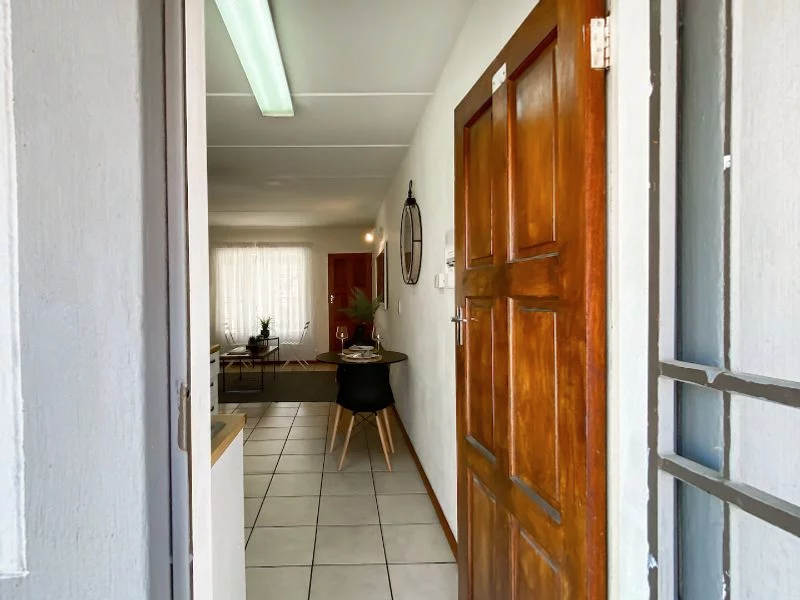 View from the entrance into the apartment, featuring tiled flooring and a wooden door leading into an open-plan living and dining area.