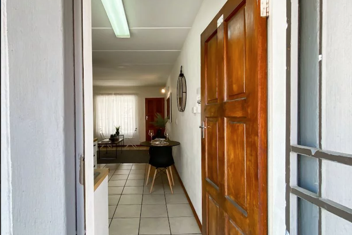 View from the entrance looking into the apartment, featuring tiled flooring and a wooden front door leading into an open-plan living area.