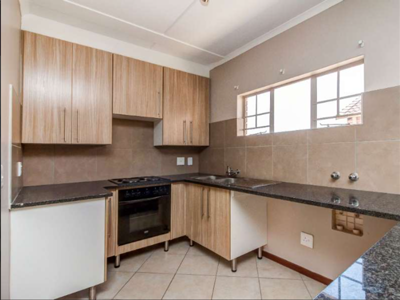 A functional kitchen featuring laminate cabinetry, granite countertops, a built-in oven, and a tiled backsplash, offering a practical layout for daily use.