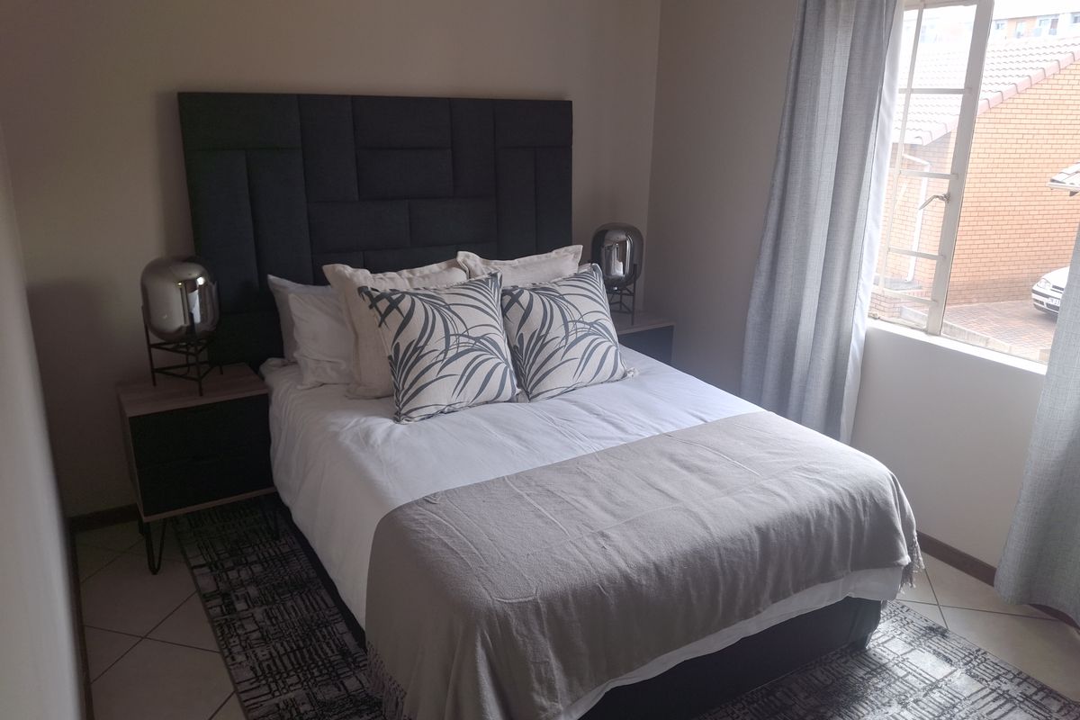 A well-maintained bedroom featuring tiled flooring and a window with natural light, providing a comfortable and functional living space.