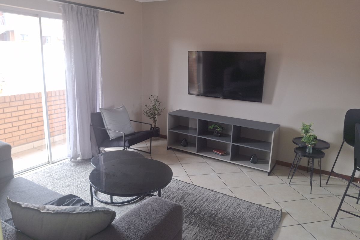 A living room featuring ceramic floor tiles and a sliding glass door providing access to an outdoor balcony area.