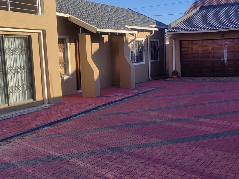 Front exterior view of the house featuring a paved driveway, double garage, and sliding doors with security gates.