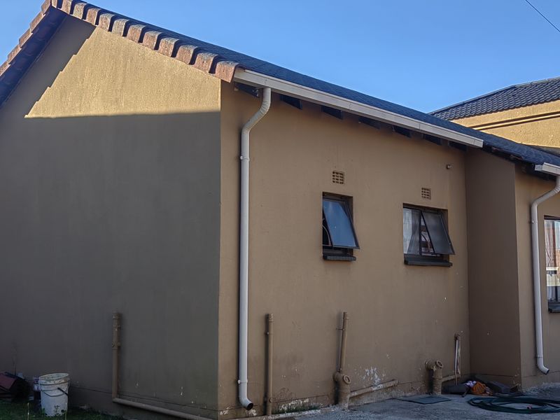 Rear exterior view of the house showing tiled roofing, guttering, and external wall finishes with visible signs of wear and maintenance requirements.