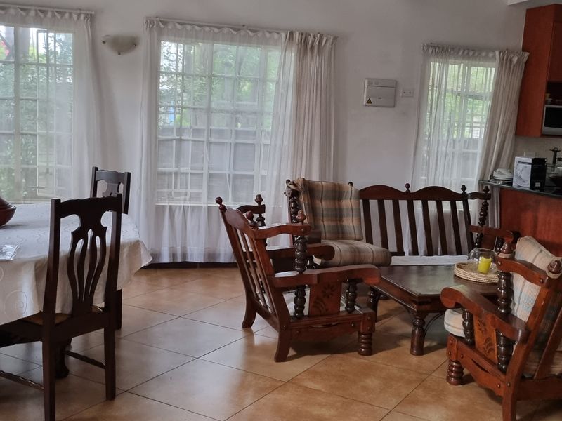 Open-plan living and dining area featuring tiled floors, large windows with natural light, and a functional kitchen with granite countertops and built-in appliances.