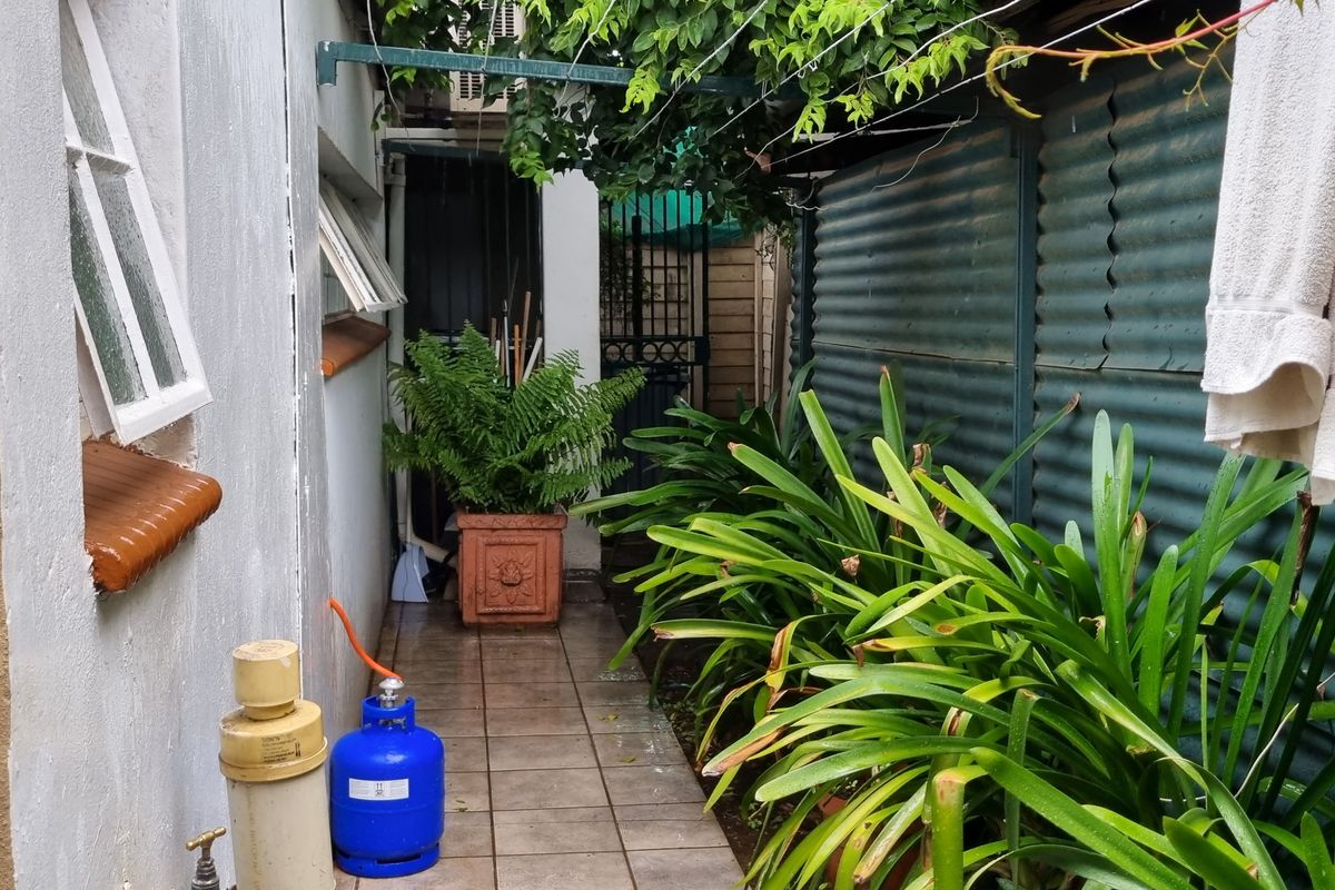 A narrow side passage or rear courtyard area featuring tiled flooring, corrugated metal wall cladding, and an overhead awning structure.