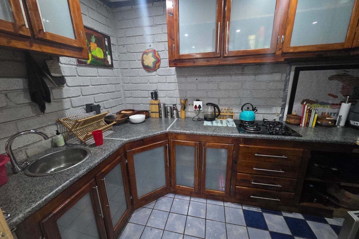 A functional kitchen featuring dark wood cabinetry with glass inserts, granite-style countertops, a gas hob, and a stainless steel sink.