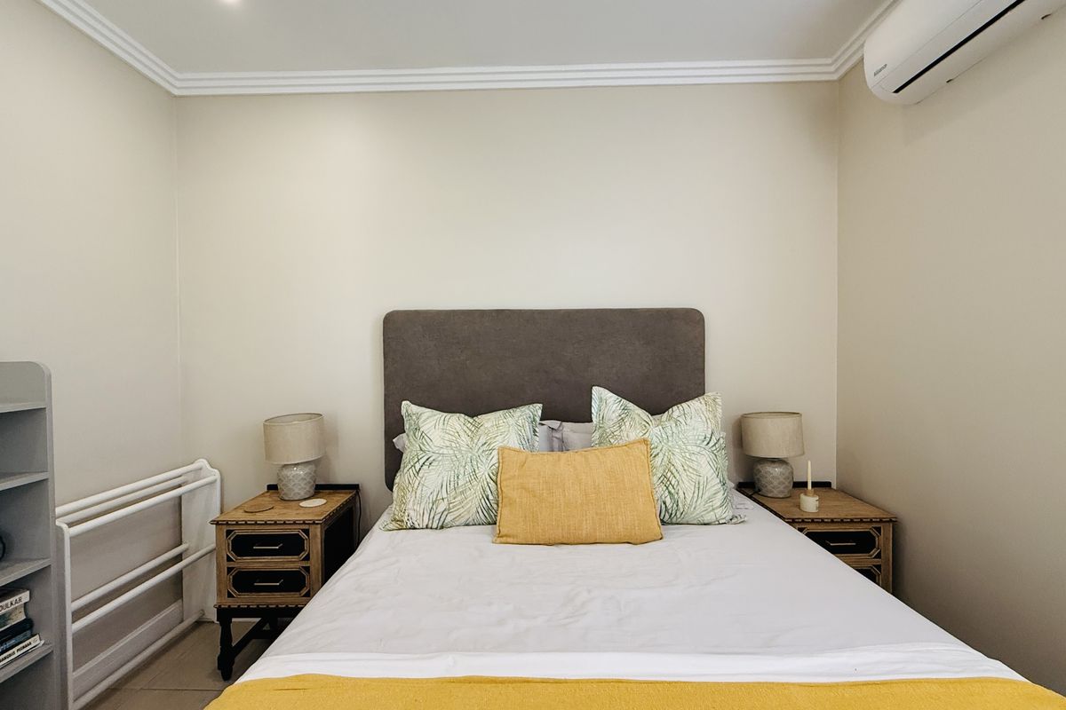 A well-maintained bedroom featuring crown molding and a wall-mounted air conditioning unit.