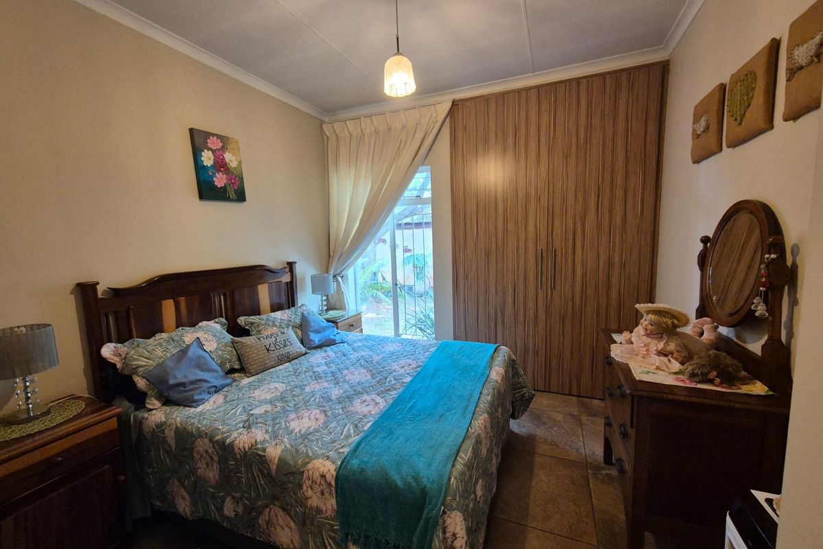 A cozy bedroom featuring built-in wooden wardrobes, tiled flooring, and a window providing natural light.