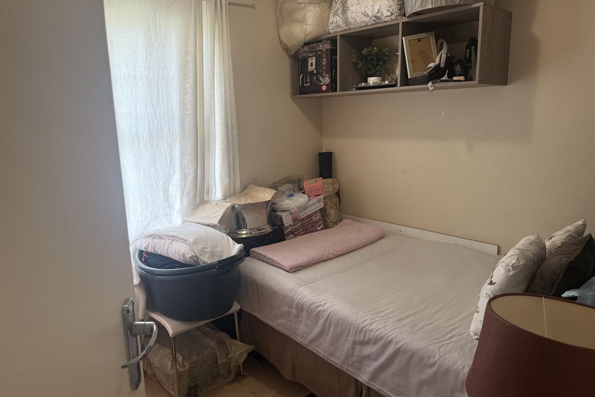 A compact bedroom featuring tiled flooring and built-in overhead shelving, providing functional storage space.