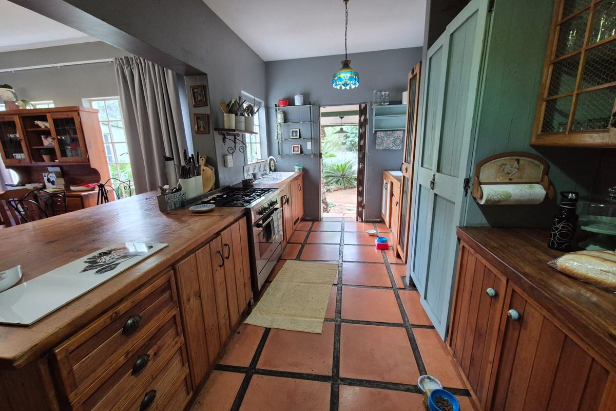 A rustic kitchen featuring wooden cabinetry, a gas stove, and terracotta tiled flooring, with direct access to the outdoor garden area.