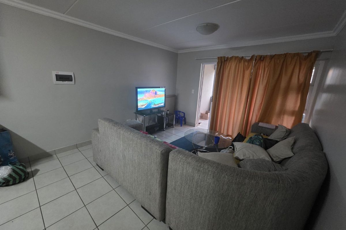 A living room featuring tiled flooring, crown molding, and a sliding door providing access to an outdoor area.