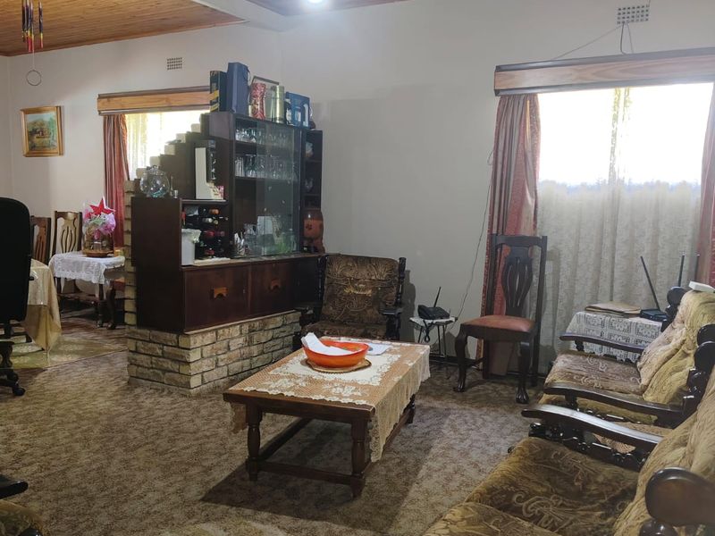 Spacious living area featuring a timber-clad ceiling, brick-based room divider, and carpeted flooring, offering a traditional layout with potential for modernization.