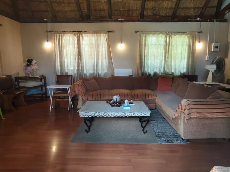 Spacious living room featuring a high vaulted thatched ceiling, exposed timber beams, and laminate wood flooring.