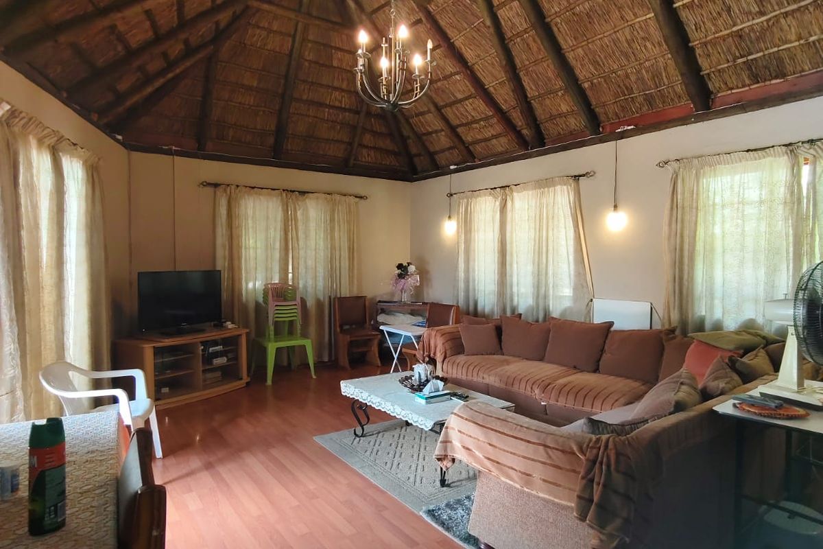 Spacious living area featuring a high vaulted thatch ceiling with exposed timber beams and laminate wood flooring.