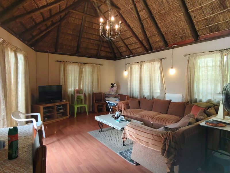 Spacious living area featuring a high vaulted thatch ceiling with exposed timber beams and laminate wood flooring.