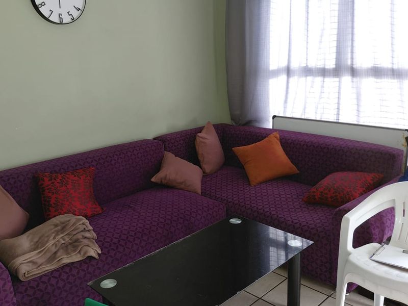 A living room area featuring tiled flooring and a large window, providing natural light to the space.