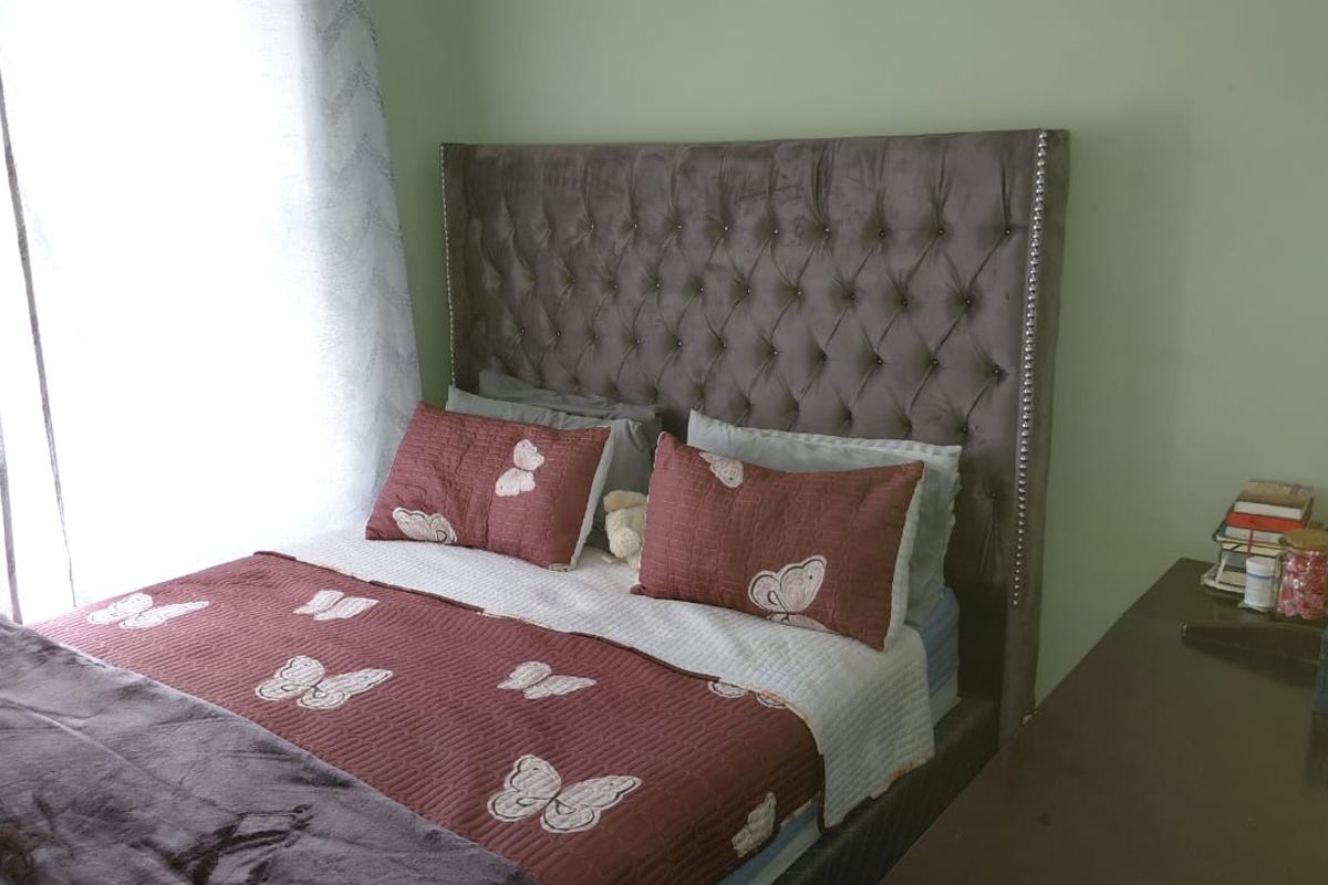 A bedroom featuring a tufted upholstered headboard and natural light from the adjacent window.