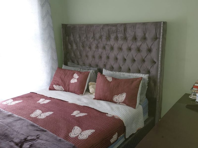 A bedroom featuring a tufted upholstered headboard and natural light from the adjacent window.