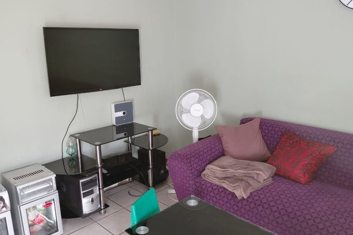 A living room area featuring tiled flooring and neutral wall finishes, providing a functional space for relaxation.