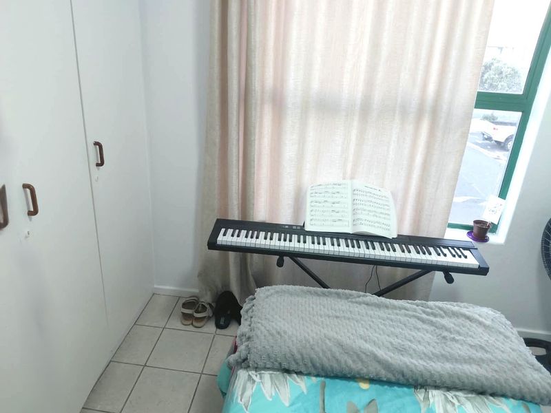A bedroom featuring built-in cupboards, tiled flooring, and a large window allowing natural light into the space.