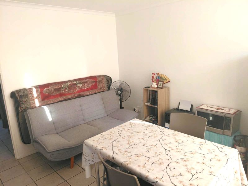 A functional living area featuring tiled flooring and coved ceiling details, providing a neutral base for potential interior updates.