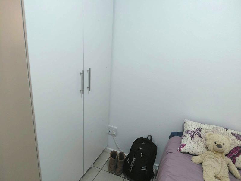 A bedroom featuring a white built-in wardrobe with modern handles and tiled flooring.