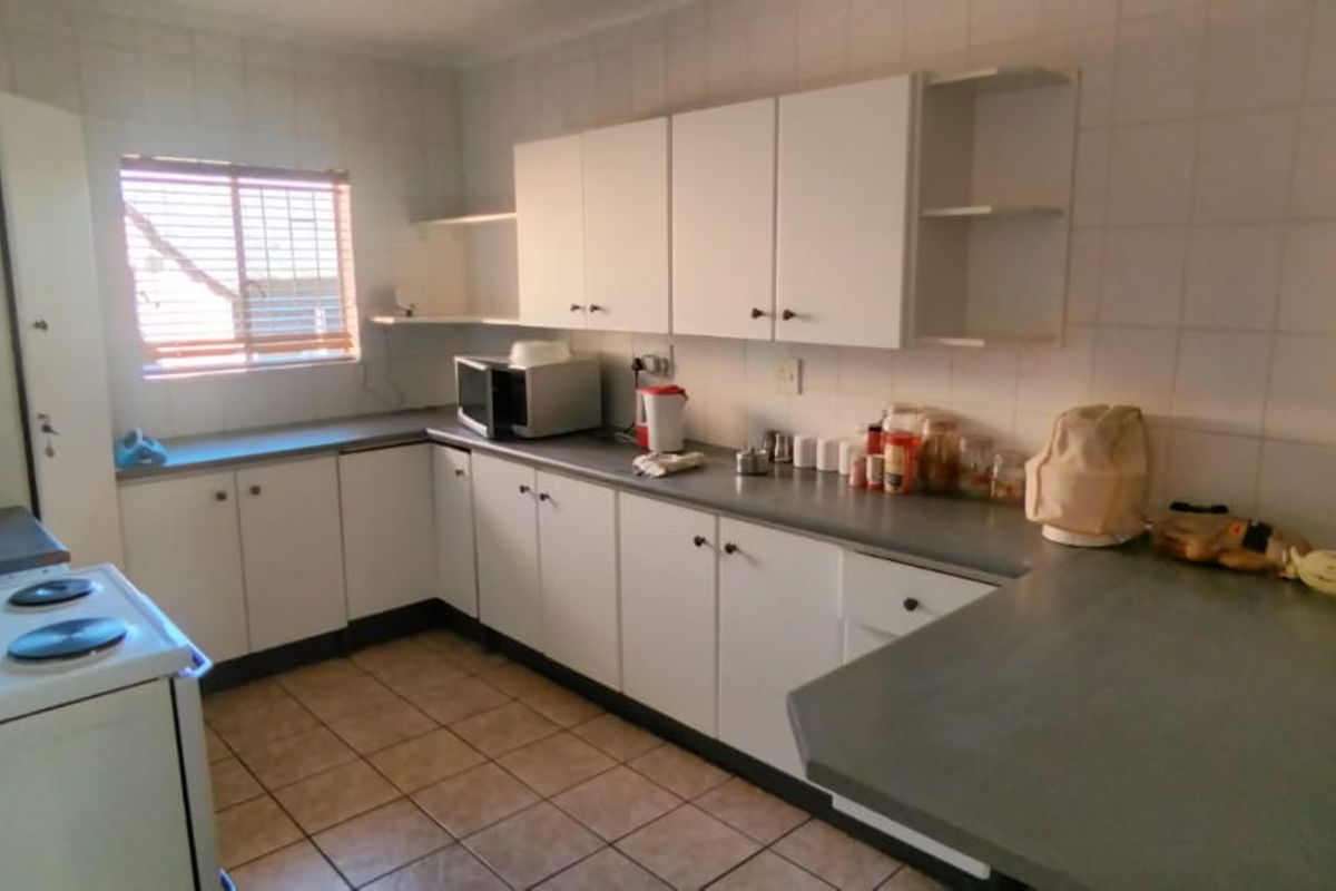 A functional kitchen featuring white cabinetry, tiled walls, and a breakfast counter, providing a practical layout for daily meal preparation.
