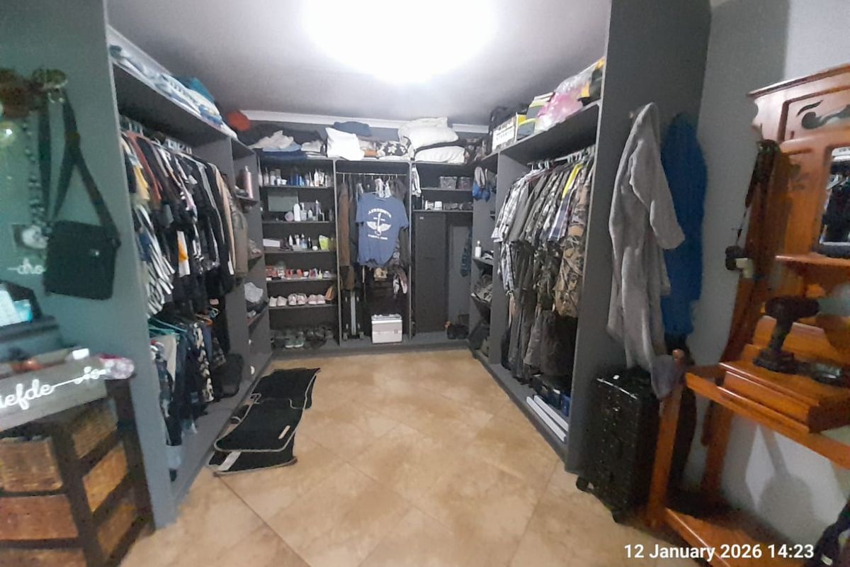 A spacious walk-in closet featuring extensive built-in cabinetry, shelving, and hanging rails, finished with tiled flooring.