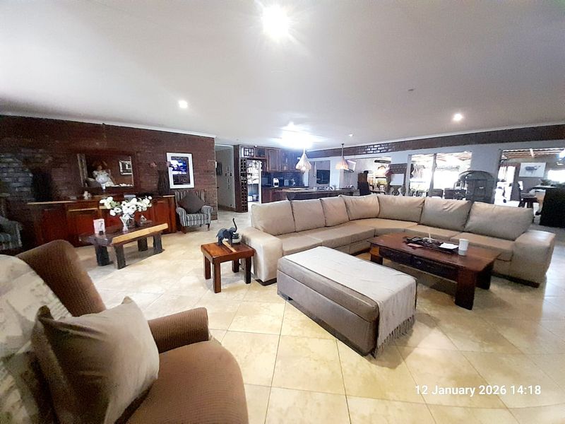 Spacious open-plan living area featuring exposed brick feature walls, tiled flooring, and recessed downlighting, seamlessly connecting to the kitchen and dining space.