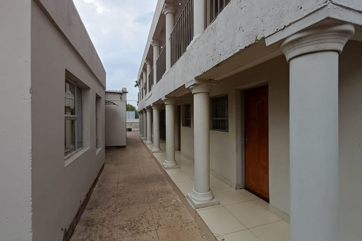 Exterior view of a multi-level residential building featuring a covered walkway with classical-style columns and tiled flooring.