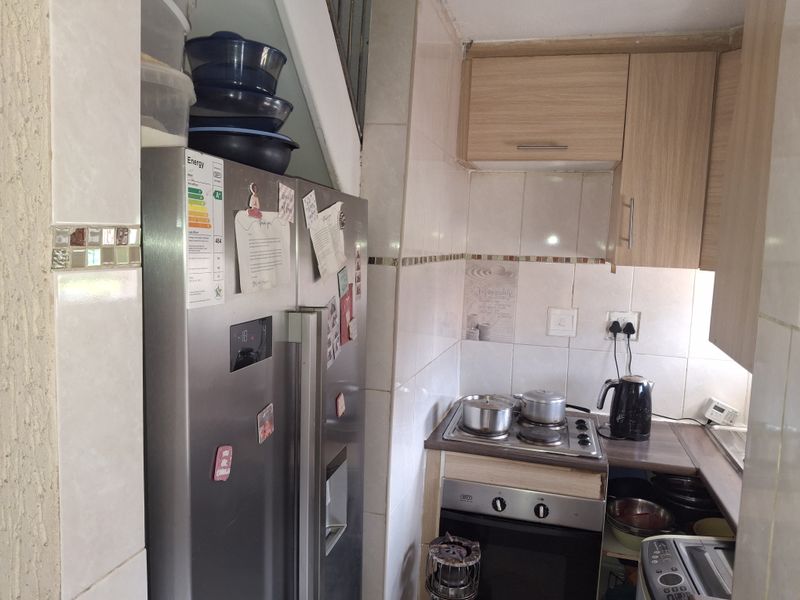 Compact kitchen featuring built-in cabinetry, tiled backsplash, and integrated electric oven and hob setup.