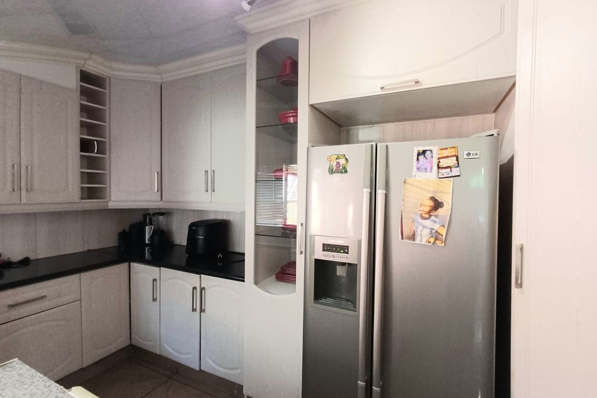 A functional kitchen featuring light-toned cabinetry, dark countertops, and a dedicated space for a large refrigerator.