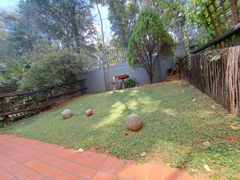 A private garden area featuring a brick-paved patio, lawn, and secure boundary walling with wooden fencing.