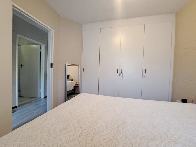 A bedroom featuring built-in cupboards and a doorway leading to an adjacent room.