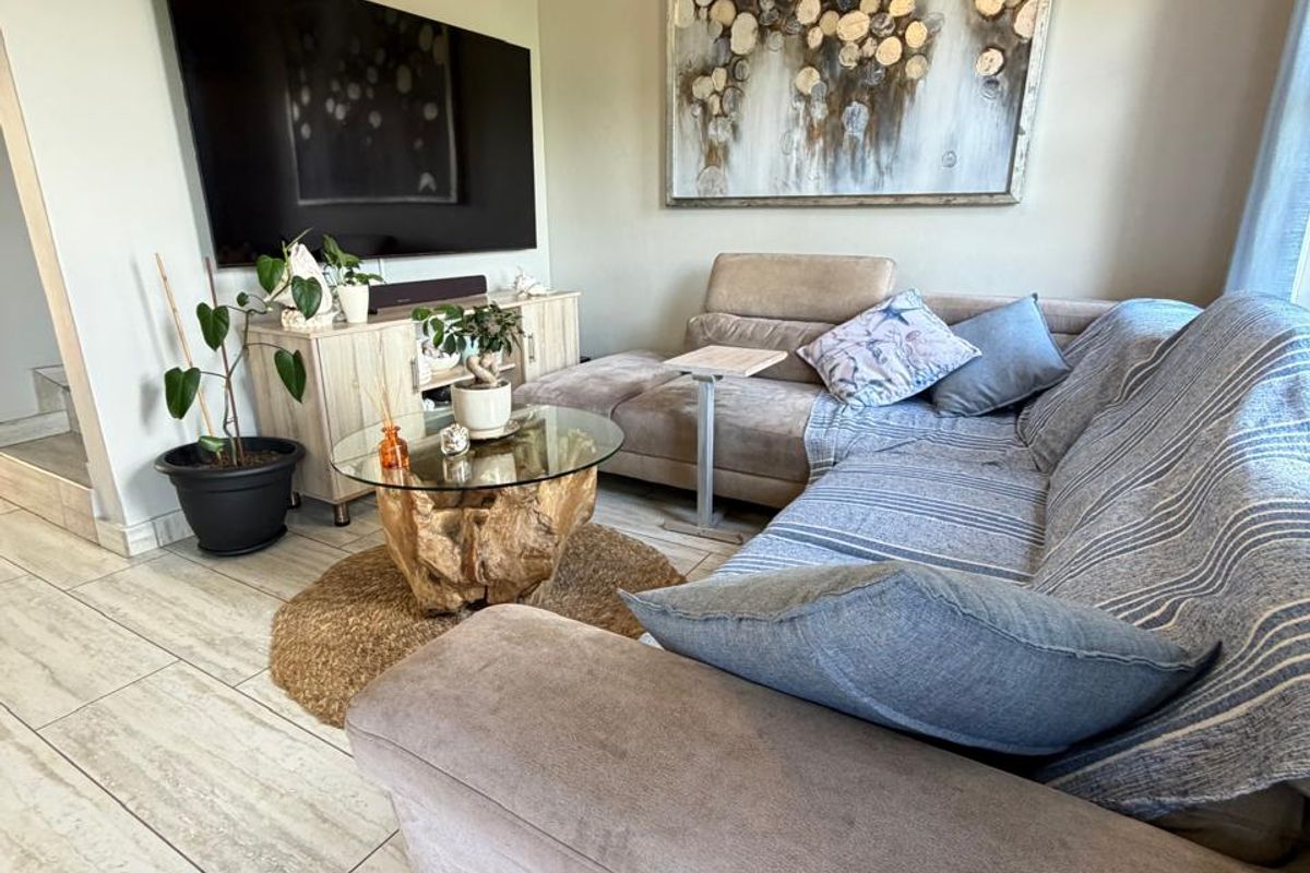 A comfortable living room featuring large format floor tiles and a neutral color palette, providing a functional and inviting space for relaxation.