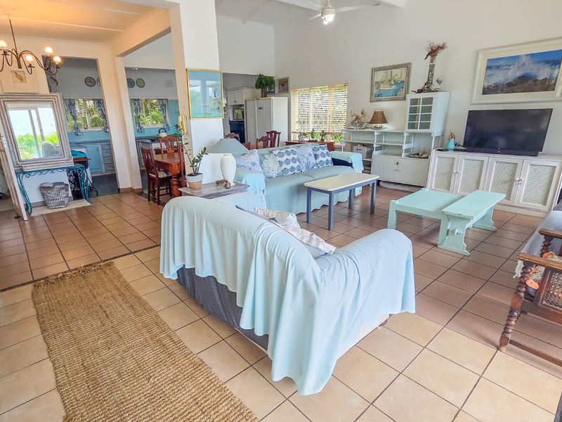 Spacious open-plan living area featuring ceramic tile flooring, high ceilings with a fan, and integrated cabinetry, offering a versatile layout for family living.