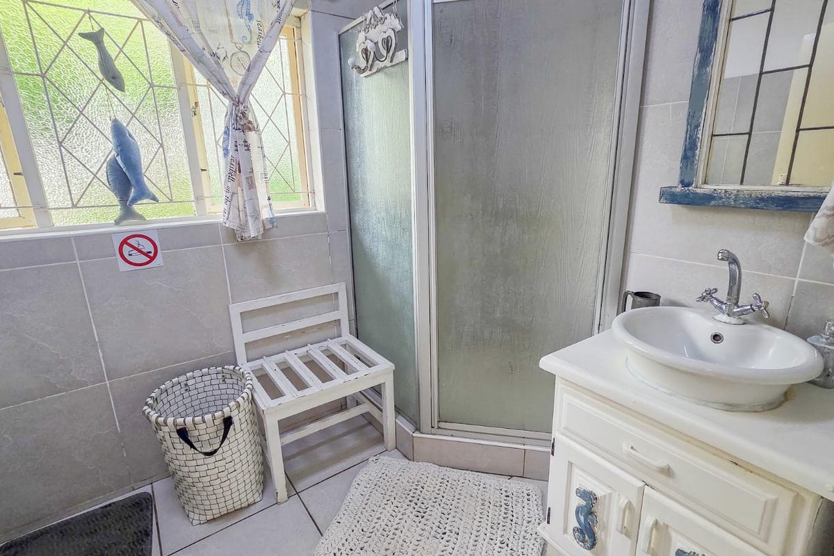 A functional bathroom featuring a shower enclosure, vanity basin, and neutral tiled finishes, providing a clean and practical space.