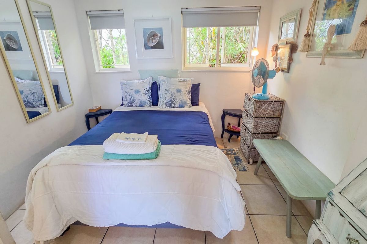 A compact bedroom featuring tiled flooring, security bars on the windows, and roller blinds, offering a functional and well-lit sleeping space.