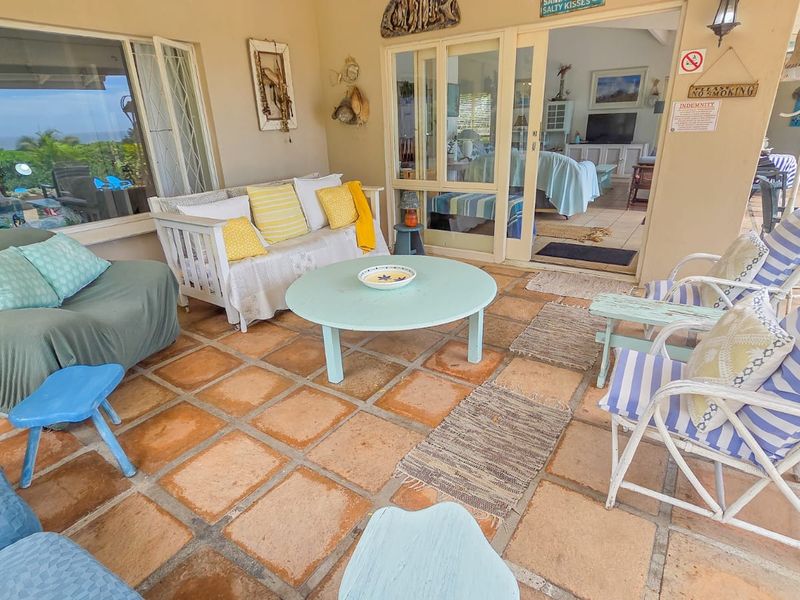 A covered patio area featuring terracotta floor tiles and sliding glass door access to the interior living space.