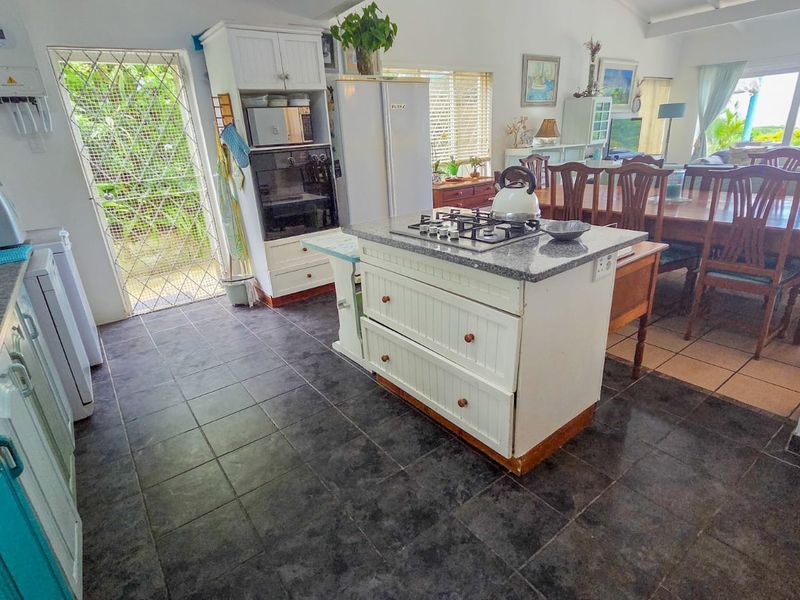 Open-plan kitchen and dining area featuring a central island with gas hob, built-in oven, and tiled flooring, providing a functional space for cooking and dining.