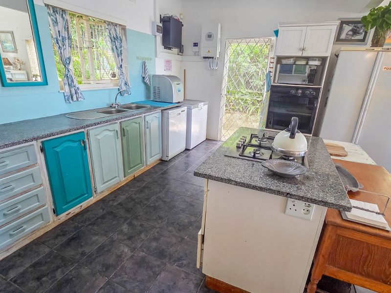 A functional kitchen featuring granite countertops, a built-in oven, gas hob, and ample cabinetry, with direct access to the exterior via a security gate.