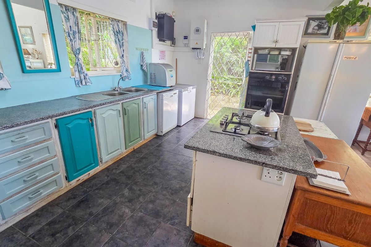 A functional kitchen featuring granite countertops, a built-in oven, gas hob, and ample cabinetry, with direct access to the exterior via a security gate.