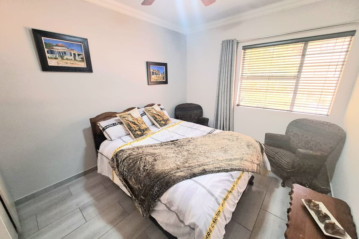 A bedroom featuring tiled flooring, a ceiling fan, and window blinds, providing a functional and comfortable living space.