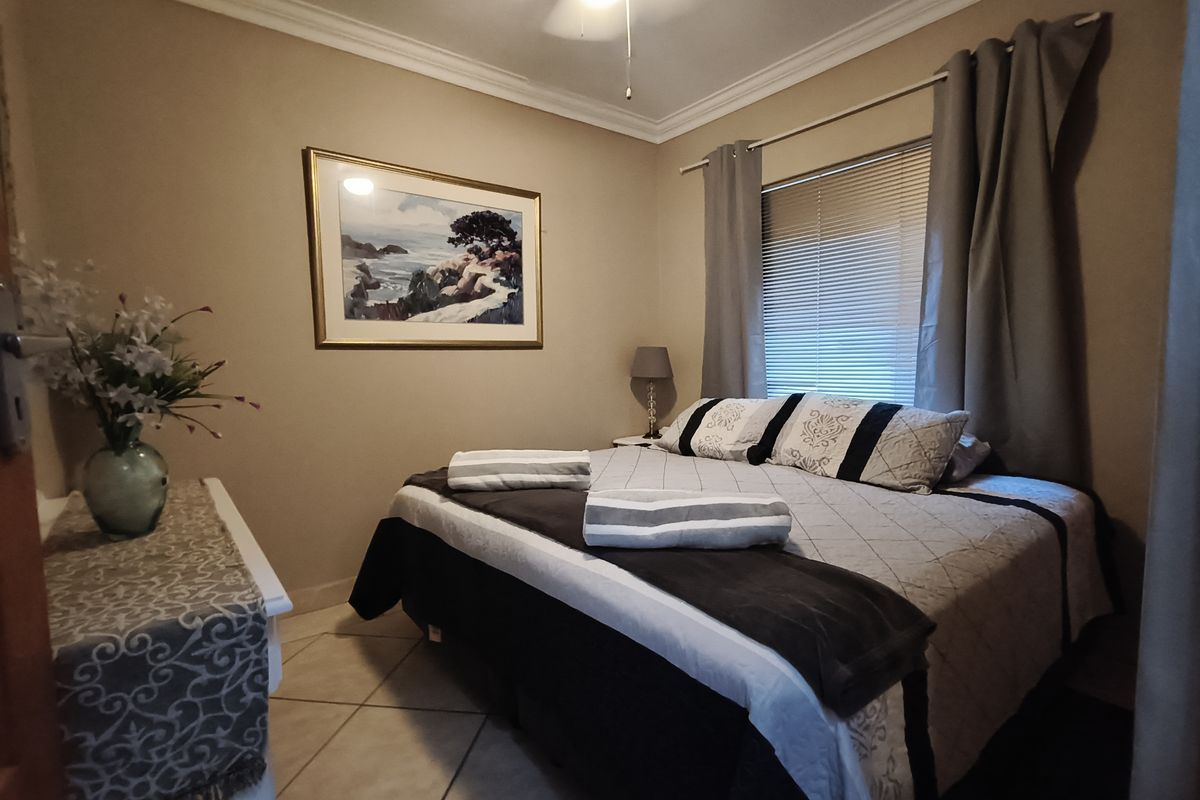 A cozy bedroom featuring tiled flooring, crown molding, and a ceiling fan, providing a comfortable and functional sleeping space.