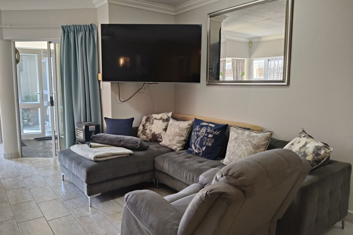 A living room featuring tiled flooring, crown molding, and a sliding glass door providing access to an outdoor patio area.