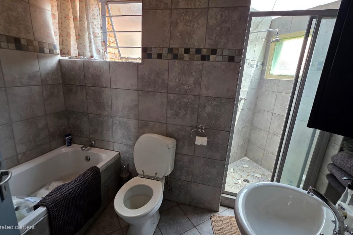 A functional bathroom featuring a built-in bathtub, a separate glass-enclosed shower, a toilet, and a pedestal basin with full-height wall tiling.