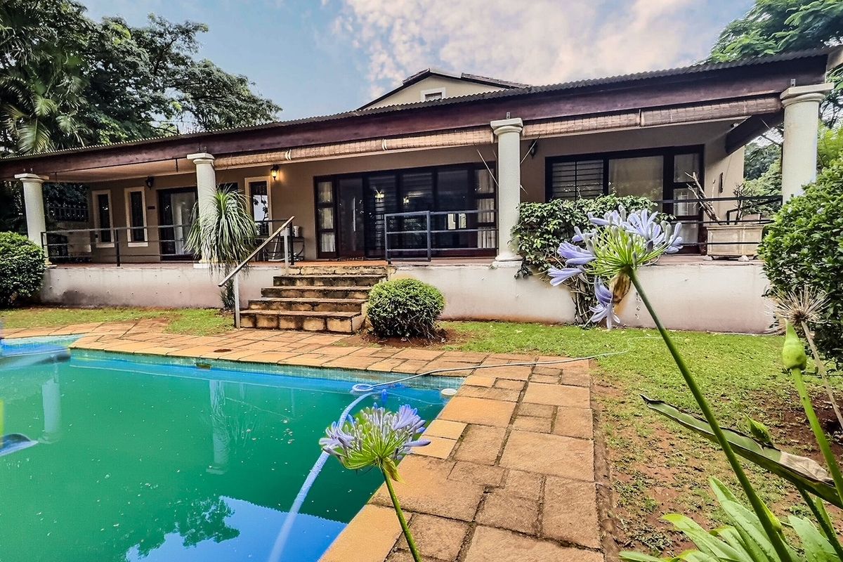 Rear view of the property featuring a covered patio, swimming pool, and landscaped garden area.